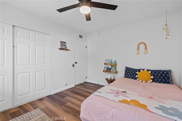 bedroom featuring ceiling fan, visible vents, a closet, baseboards, and wood finished floors