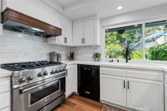 kitchen with stainless steel stove, black dishwasher, light countertops, white cabinets, and premium range hood