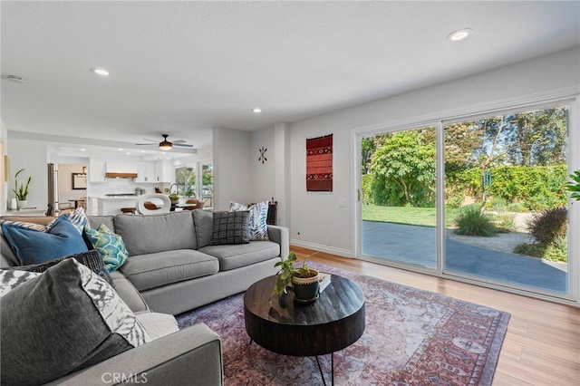 living room featuring recessed lighting, a ceiling fan, baseboards, and light wood-style floors