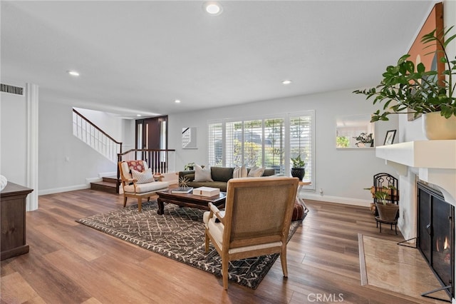 living area with wood finished floors, recessed lighting, and stairs