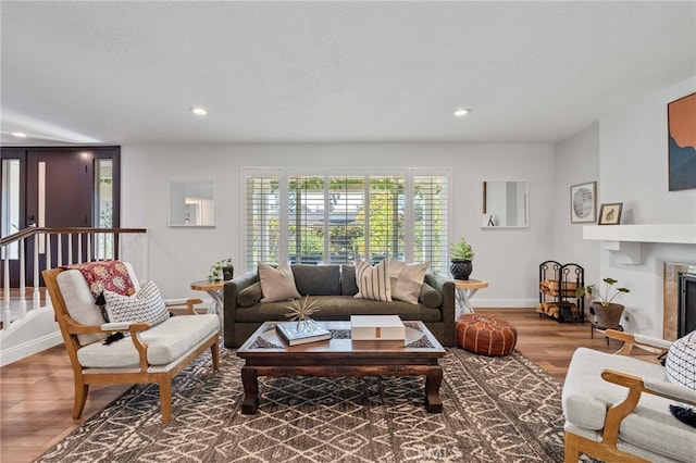 living room featuring a fireplace, recessed lighting, wood finished floors, and baseboards