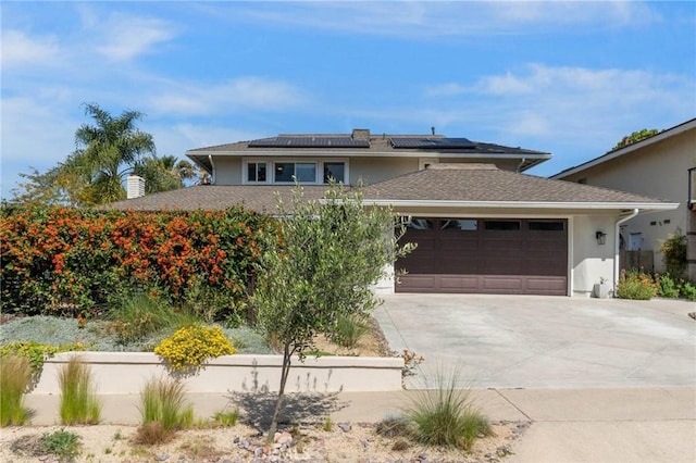 view of front of house featuring driveway, solar panels, stucco siding, and an attached garage