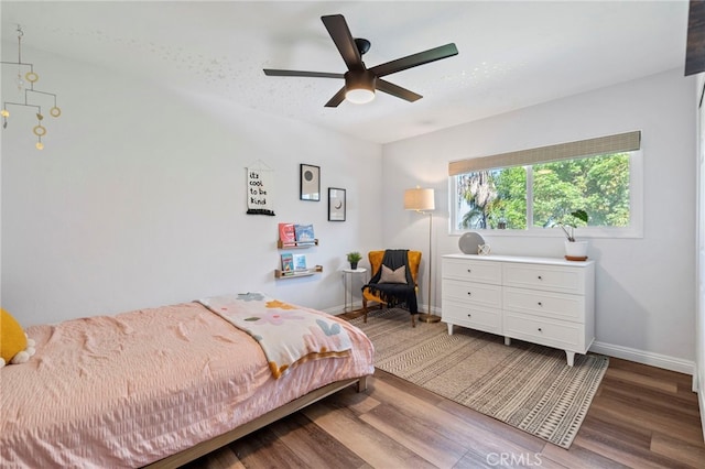 bedroom with ceiling fan, wood finished floors, and baseboards