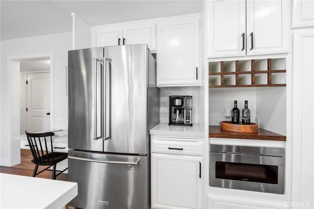 kitchen with white cabinetry, dark wood-type flooring, light countertops, and high end refrigerator