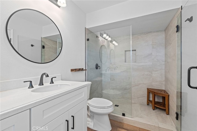 full bathroom featuring wood finished floors, vanity, toilet, and a stall shower