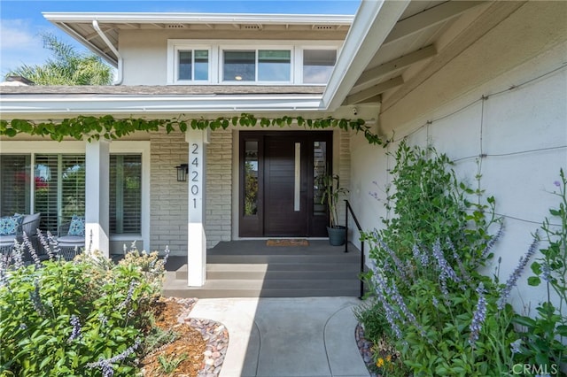 doorway to property with a porch and stucco siding