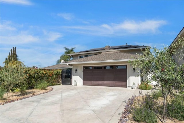 view of front of home featuring roof mounted solar panels, concrete driveway, a garage, and stucco siding