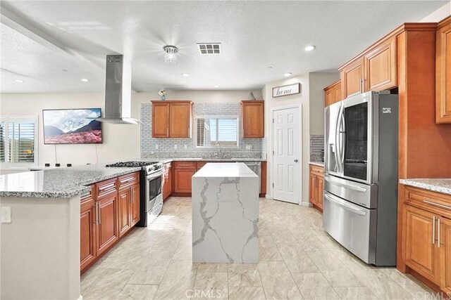5491 N Pinnacle Ln, San Bernardino, CA 92407 - kitchen featuring appliances with stainless steel finishes, island exhaust hood, a kitchen island, tasteful backsplash, and plenty of natural light