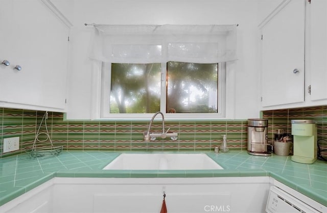 11767 W Sunset Blvd Unit 206, Los Angeles, CA 90049 - kitchen view of tile countertops, a sink, white cabinets, tasteful backsplash, and white dishwasher