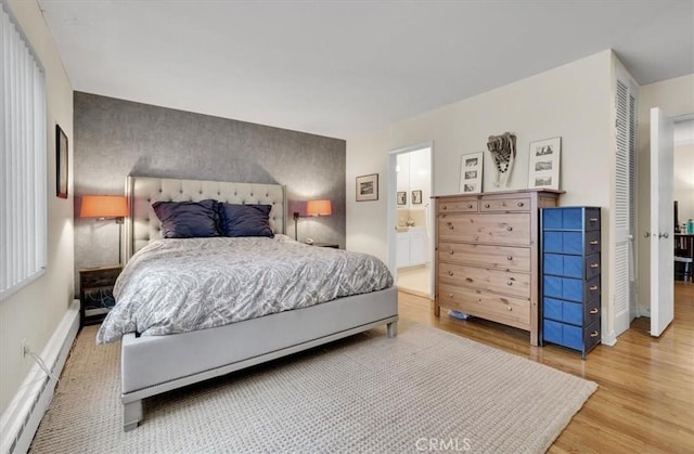 11767 W Sunset Blvd Unit 206, Los Angeles, CA 90049 - bedroom with wood finished floors, a baseboard radiator, baseboards, ensuite bathroom, and an accent wall