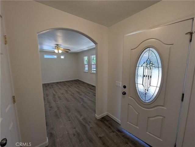 entryway featuring baseboards, arched walkways, a ceiling fan, and dark wood-style flooring