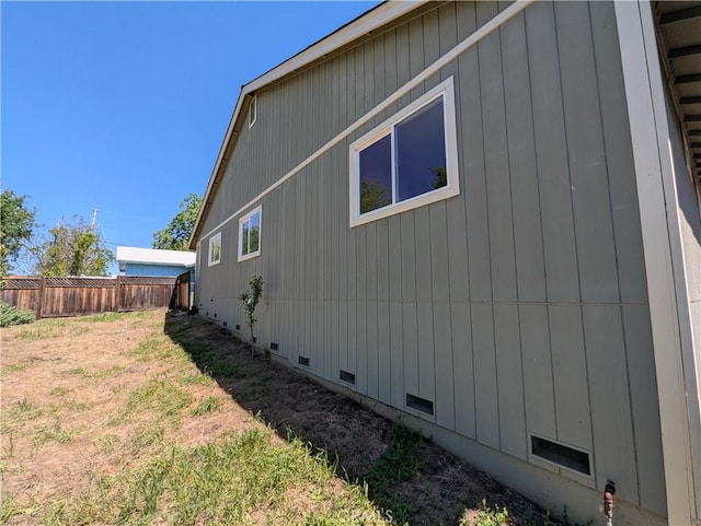 view of side of home featuring crawl space and fence