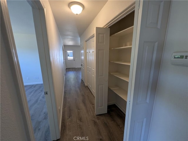 corridor featuring dark wood-style floors and baseboards
