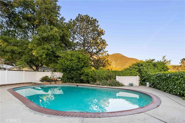 view of pool featuring a diving board, a fenced backyard, a mountain view, and a fenced in pool