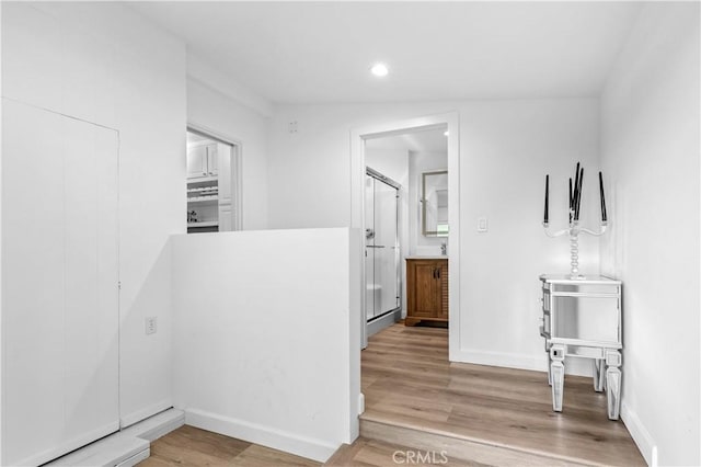 hallway with recessed lighting, light wood-style flooring, and baseboards