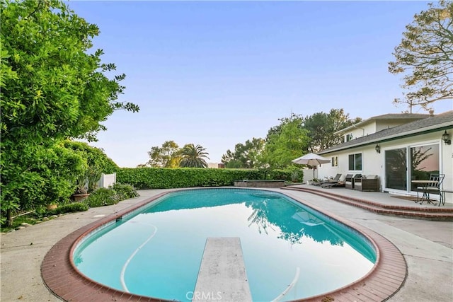 view of pool featuring a fenced in pool, a diving board, and a patio area
