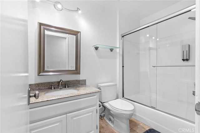 bathroom with toilet, tile patterned flooring, bath / shower combo with glass door, and vanity