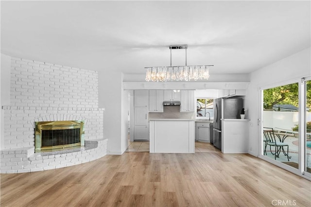 kitchen featuring pendant lighting, white cabinetry, light countertops, freestanding refrigerator, and light wood-type flooring