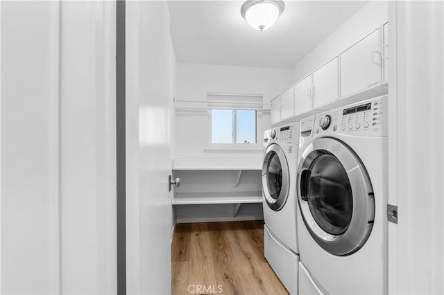washroom with cabinet space, washer and dryer, and light wood finished floors