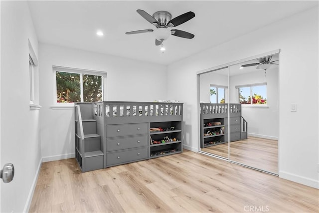 bedroom with a closet, multiple windows, wood finished floors, and baseboards