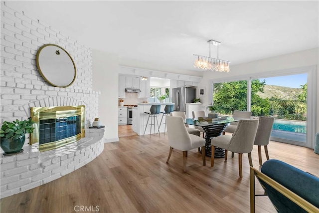 2320 Jayma Ln, La Crescenta, CA 91214 - dining area with a brick fireplace, light wood-style flooring, and a chandelier