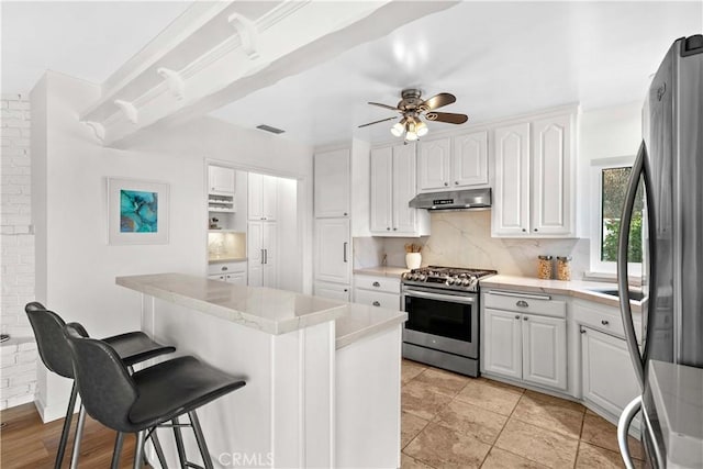 2320 Jayma Ln, La Crescenta, CA 91214 - kitchen featuring appliances with stainless steel finishes, under cabinet range hood, a breakfast bar area, and decorative backsplash