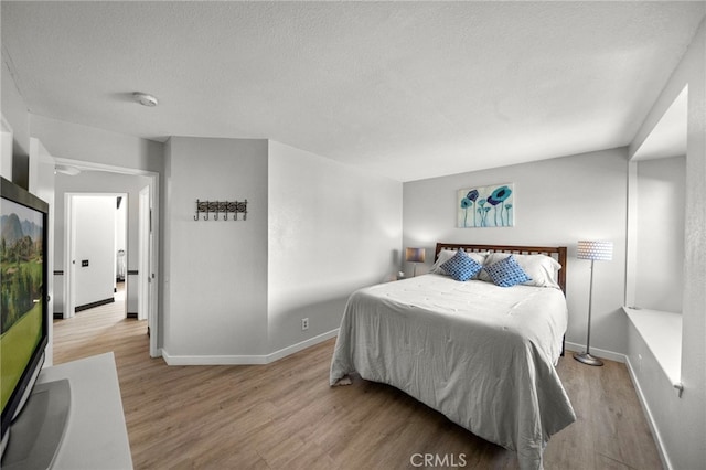 bedroom featuring a textured ceiling, wood finished floors, and baseboards