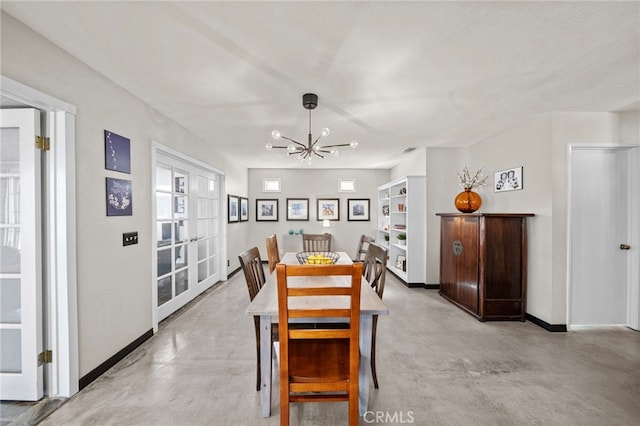 dining space with a chandelier, baseboards, and concrete floors