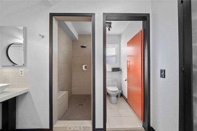 full bathroom featuring toilet, a tile shower, and tile patterned floors