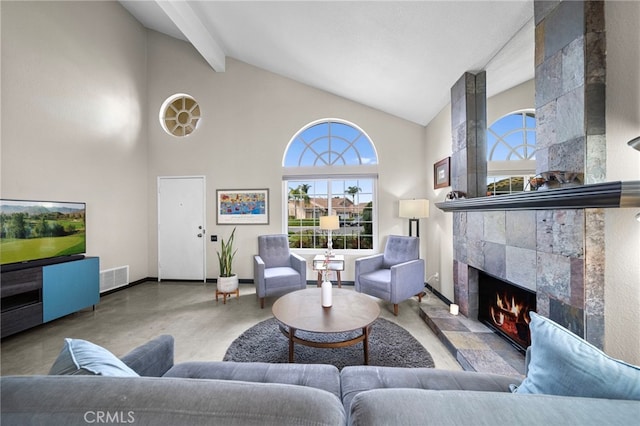 living area with beamed ceiling, concrete floors, a fireplace, visible vents, and high vaulted ceiling