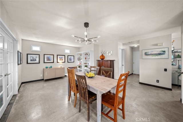 dining room with finished concrete flooring, a chandelier, and baseboards