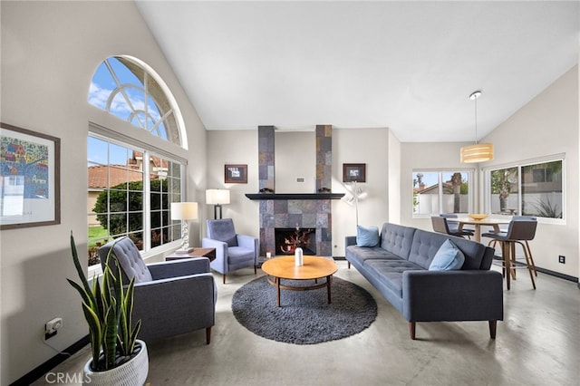 living room featuring concrete flooring, a tile fireplace, high vaulted ceiling, and baseboards