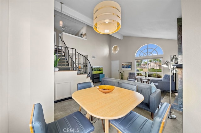dining room with beam ceiling, high vaulted ceiling, stairs, visible vents, and finished concrete floors