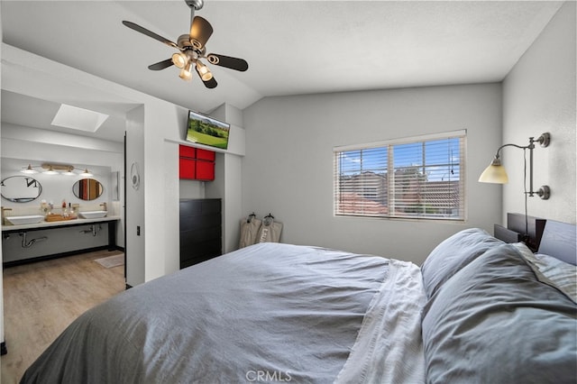 bedroom with connected bathroom, a ceiling fan, wood finished floors, and lofted ceiling with skylight