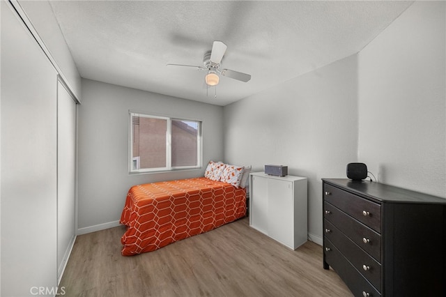 bedroom featuring a closet, ceiling fan, baseboards, and light wood-style floors