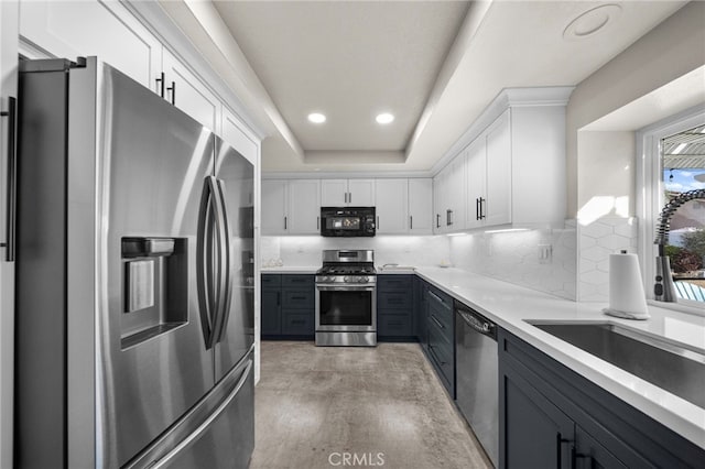 kitchen featuring white cabinetry, stainless steel appliances, decorative backsplash, and a sink