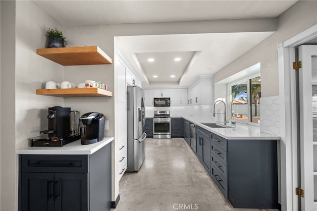kitchen with a sink, white cabinets, stainless steel appliances, and light countertops
