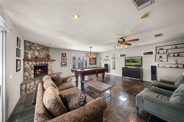 living area featuring stone tile floors, a textured ceiling, visible vents, billiards, and a stone fireplace