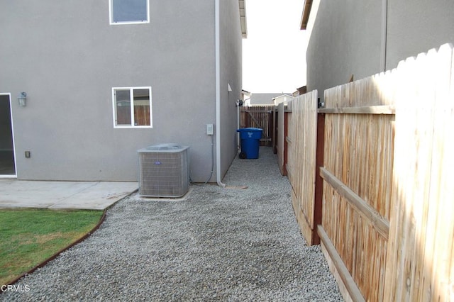 view of side of home with cooling unit, a patio, stucco siding, and fence