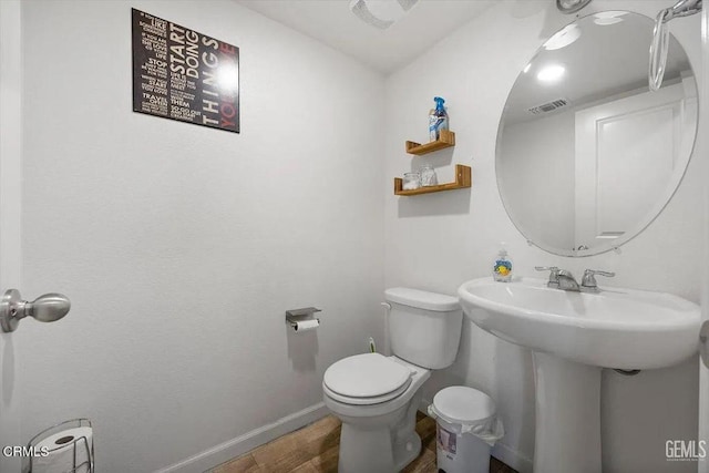bathroom featuring a sink, visible vents, baseboards, toilet, and wood finished floors