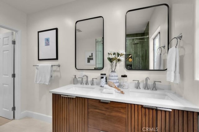 bathroom featuring double vanity, a sink, baseboards, and a stall shower