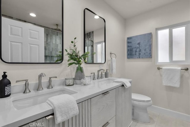 bathroom with a sink, baseboards, toilet, and double vanity