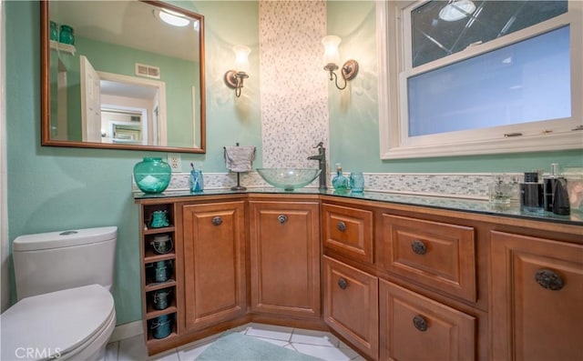 bathroom with a sink, double vanity, visible vents, toilet, and tile patterned floors
