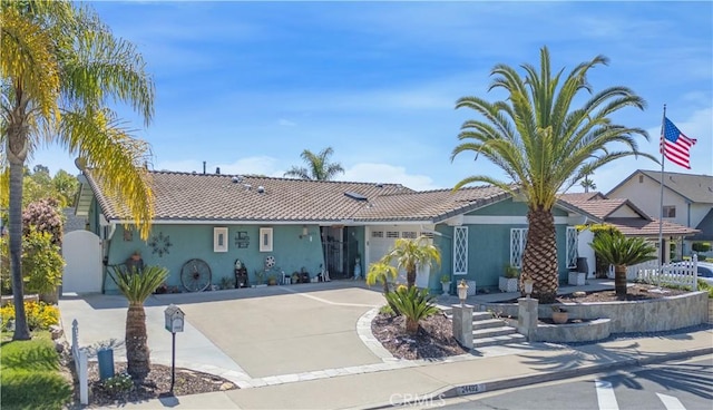 view of front of property with a tile roof, driveway, an attached garage, and stucco siding