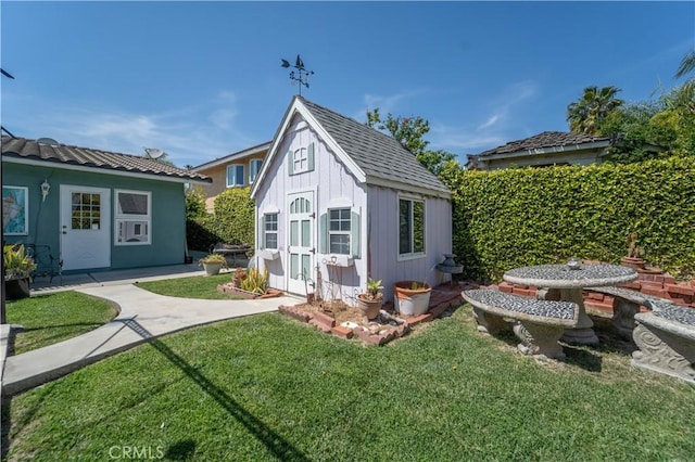 rear view of house with board and batten siding, an outdoor structure, and a lawn