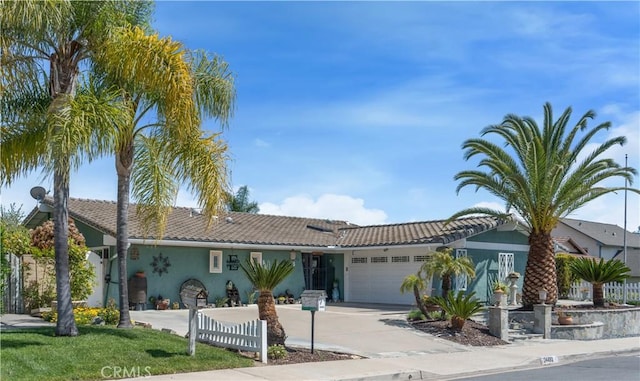 view of front of home with stucco siding, a tiled roof, fence, a garage, and concrete driveway