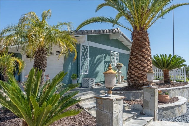 view of side of property with fence, stucco siding, and an attached garage