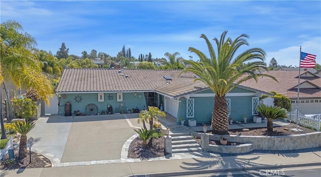 mediterranean / spanish home with fence, a tile roof, driveway, and stucco siding