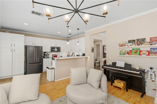 2548 S Young Ct, San Bernardino, CA 92408 - living room with crown molding, visible vents, an inviting chandelier, and light wood-type flooring