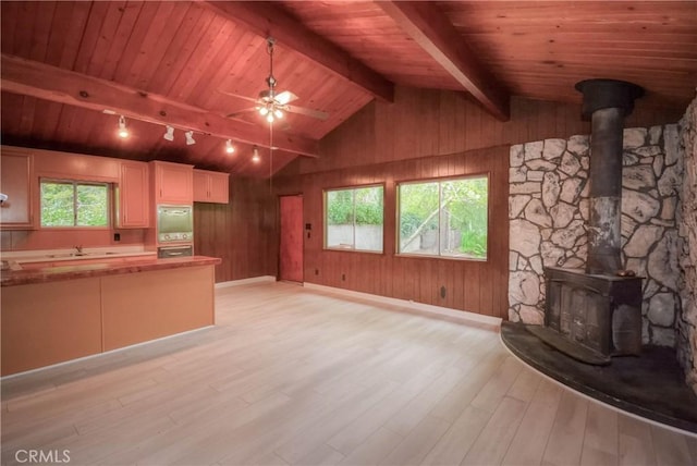 14109 Meadow Ln, Lytle Creek, CA 92358 - unfurnished living room with lofted ceiling with beams, light wood finished floors, a sink, baseboards, and a wood stove